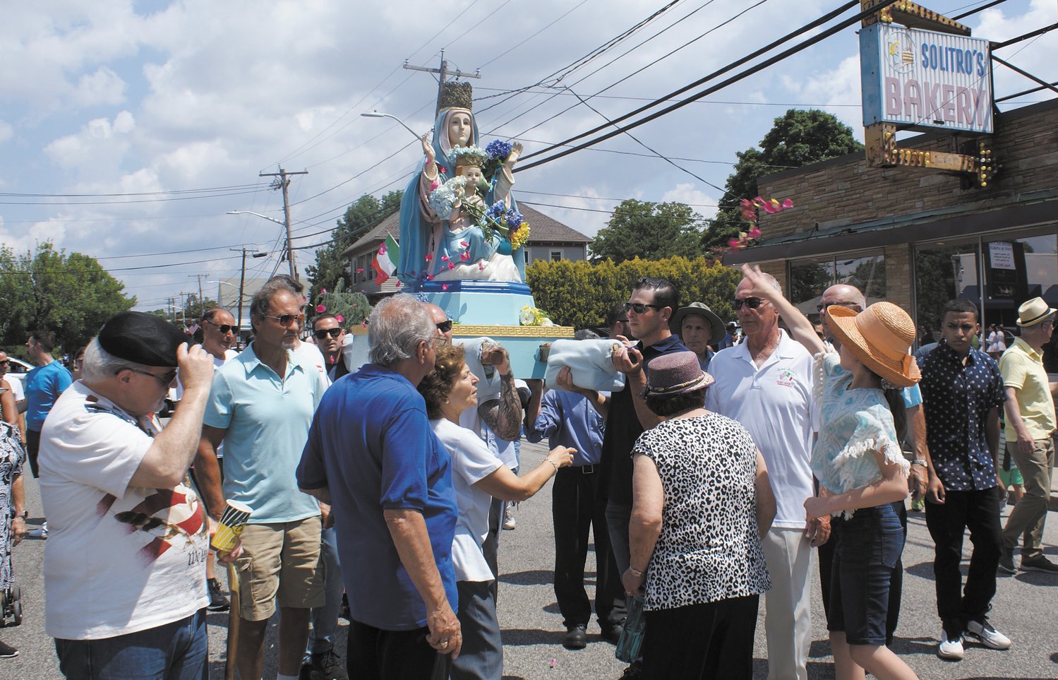 THROWING PETALS: The faithful throw rose petals on the statue of the Madonna as she is carried through the streets of Knightsville on Sunday. (Photo courtesy Steve Popiel)